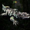 A 3D printed Sailfin Lizard fidget toy with a black, green, and yellow patterned body against a dark forest background.