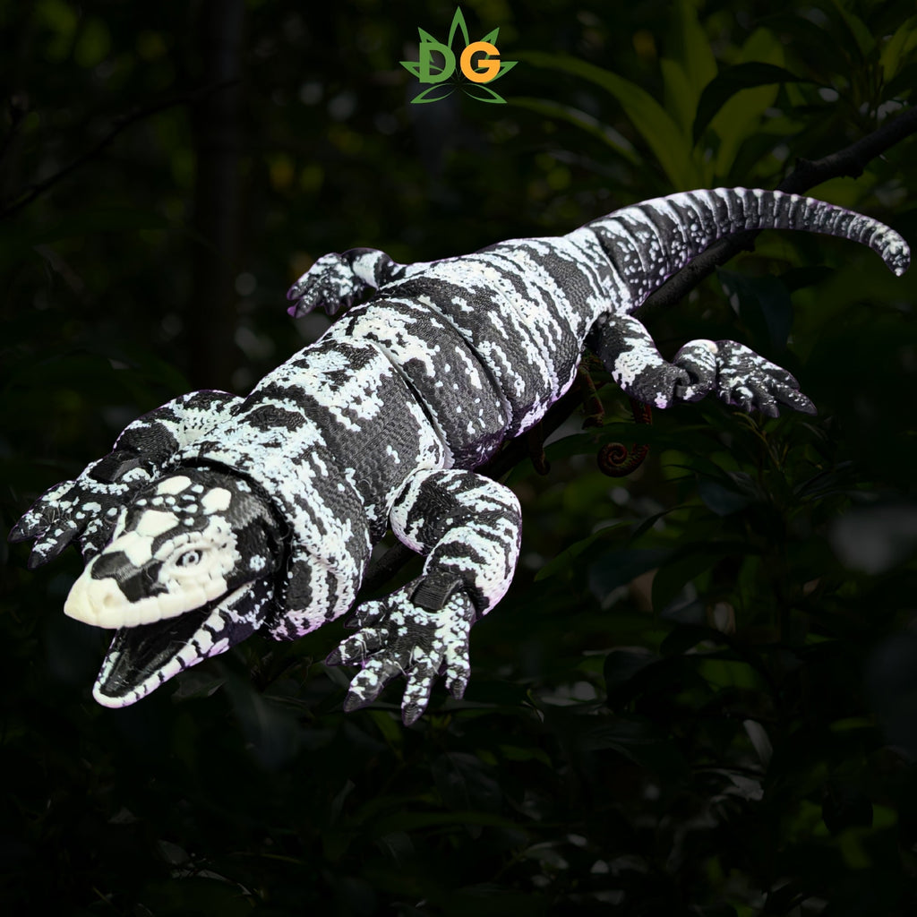 A black and white speckled 3D printed Tegu lizard perched on tree branches.